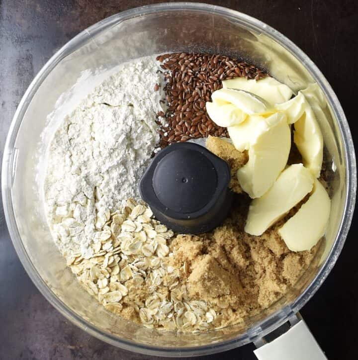 Healthy plum crumble ingredients in food processor bowl.