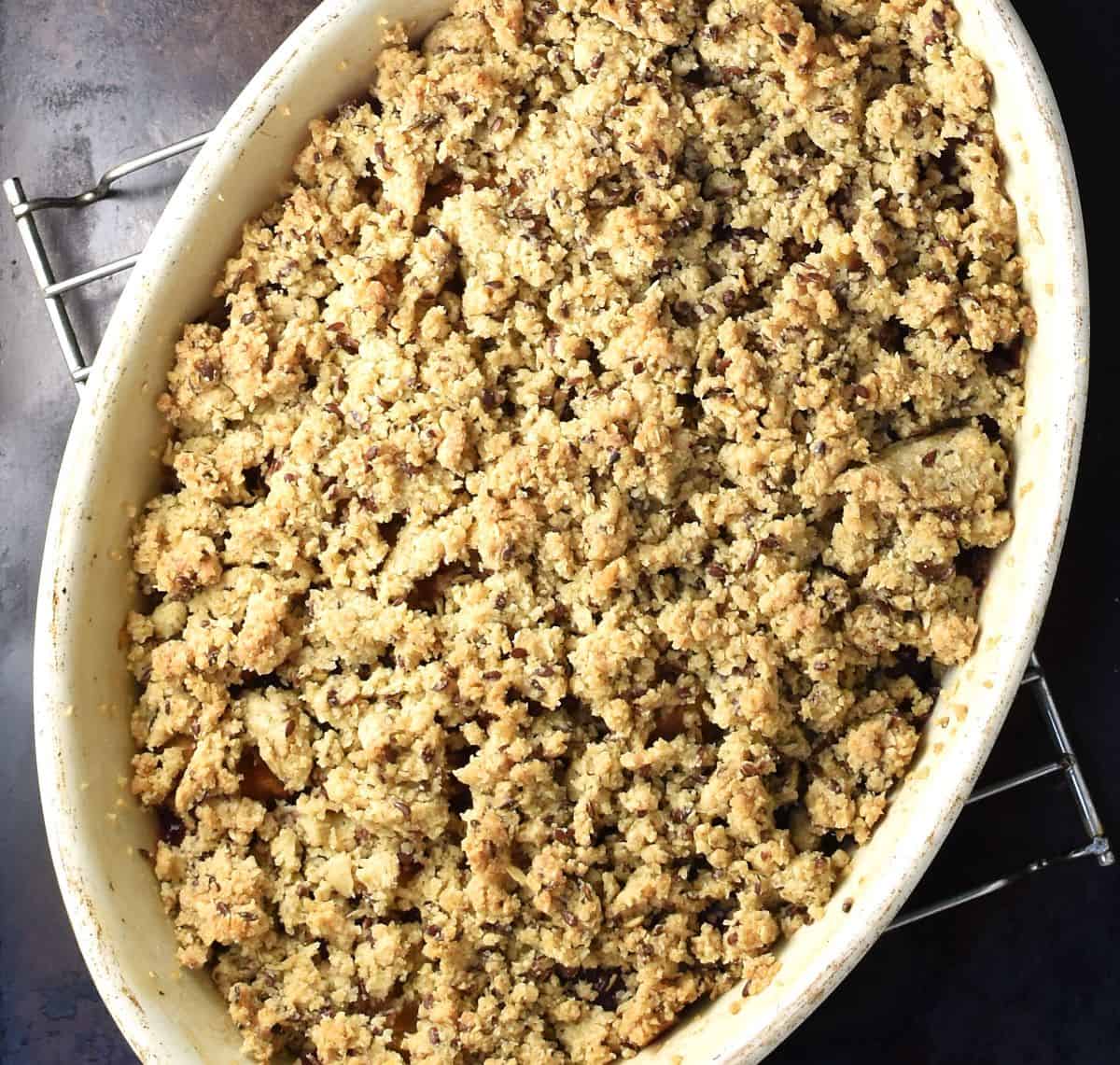 Baked plum crumble in white oval dish.