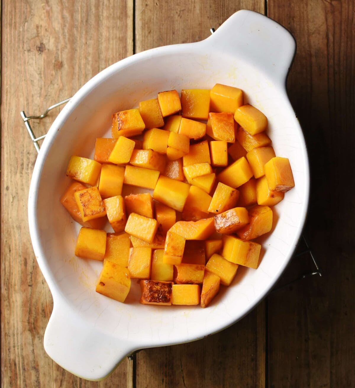 Cubed squash inside white oval casserole dish.