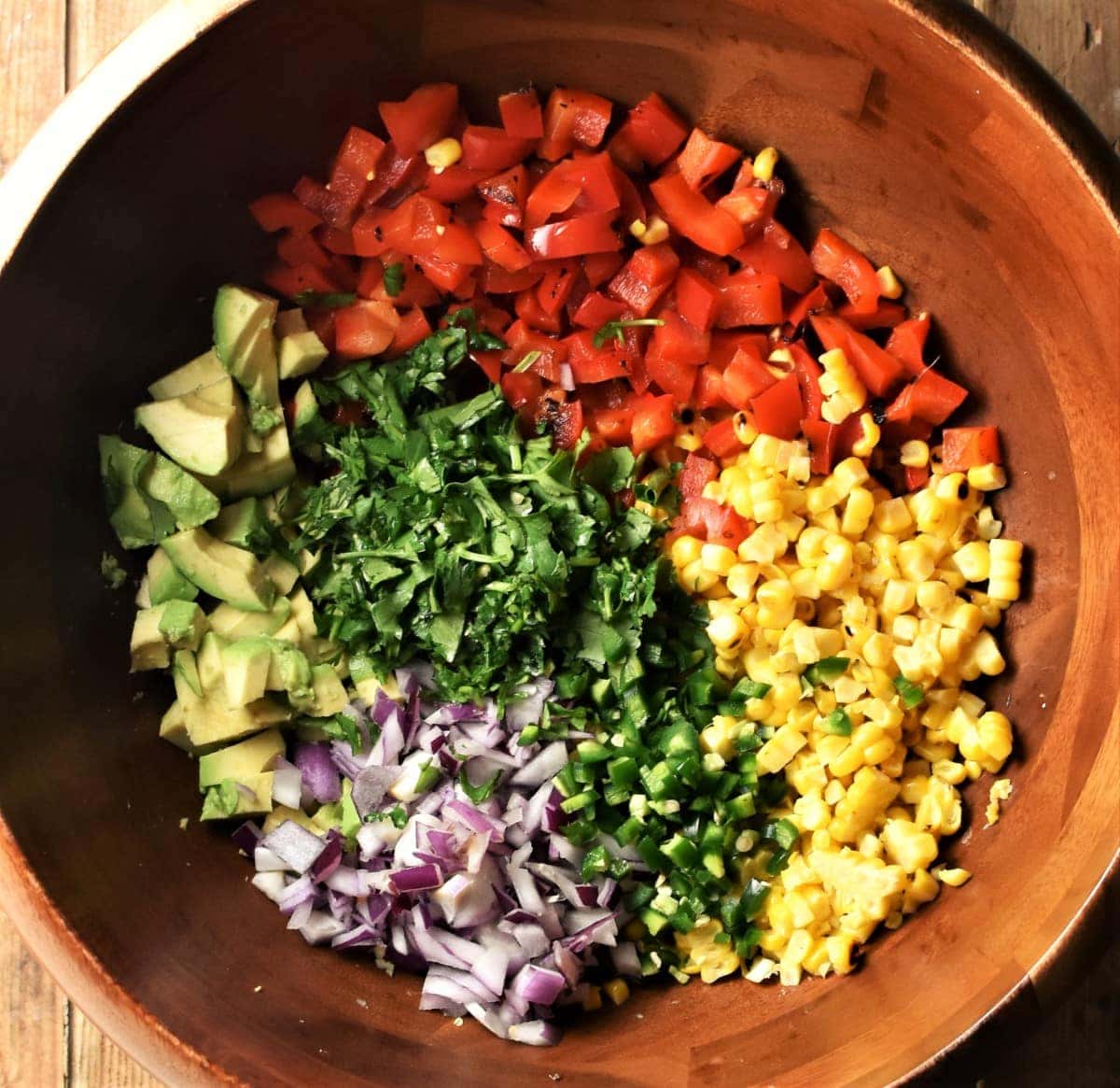 Corn and vegetable salsa ingredients in large wooden bowl.