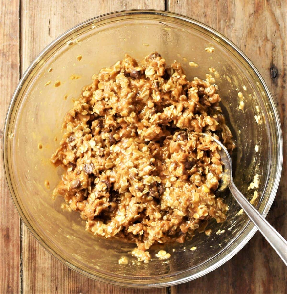 Peanut butter oatmeal cookies batter in mixing bowl with spoon.