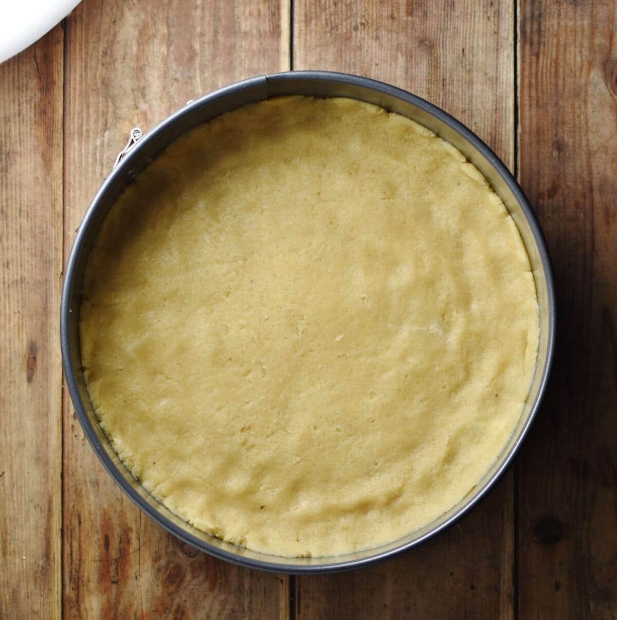 Top down view of round cake pan with dough covering the bottom.