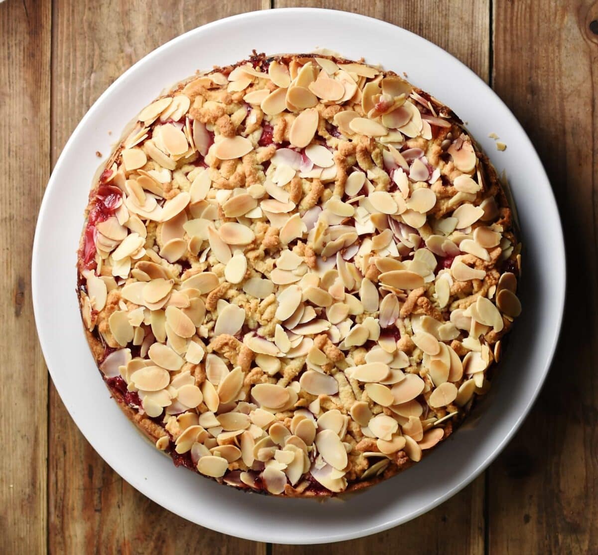 Almond redcurrant cake on top of white plate.