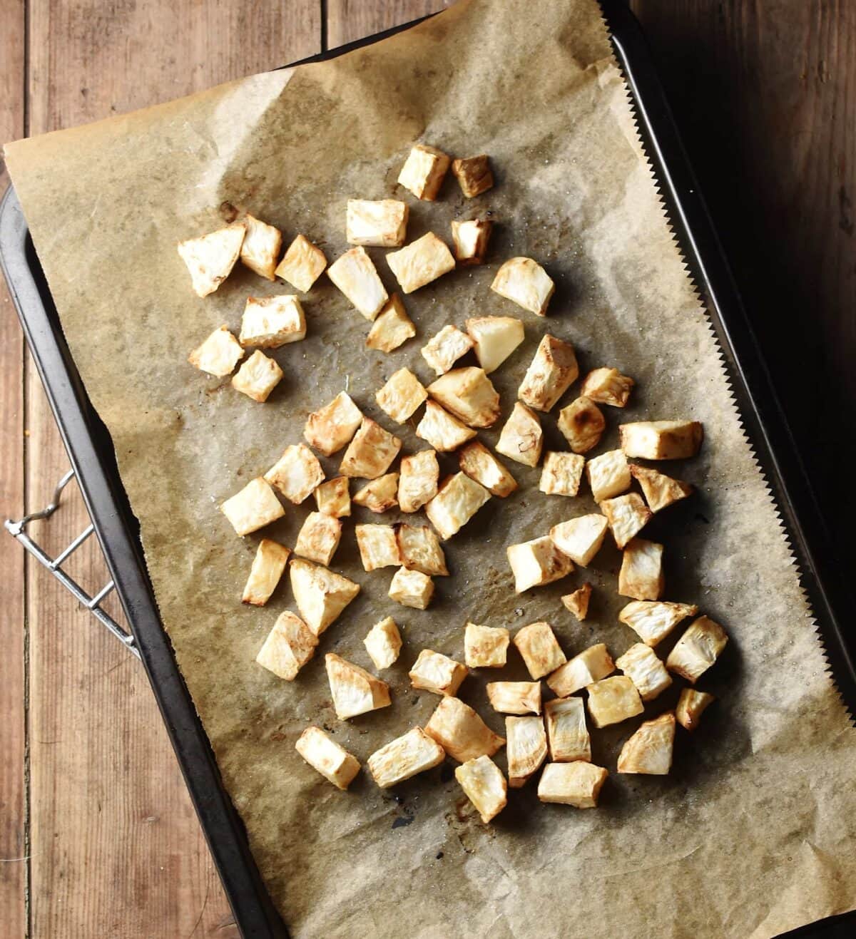 Cubed roasted celeriac on top of baking sheet lined with parchment paper.