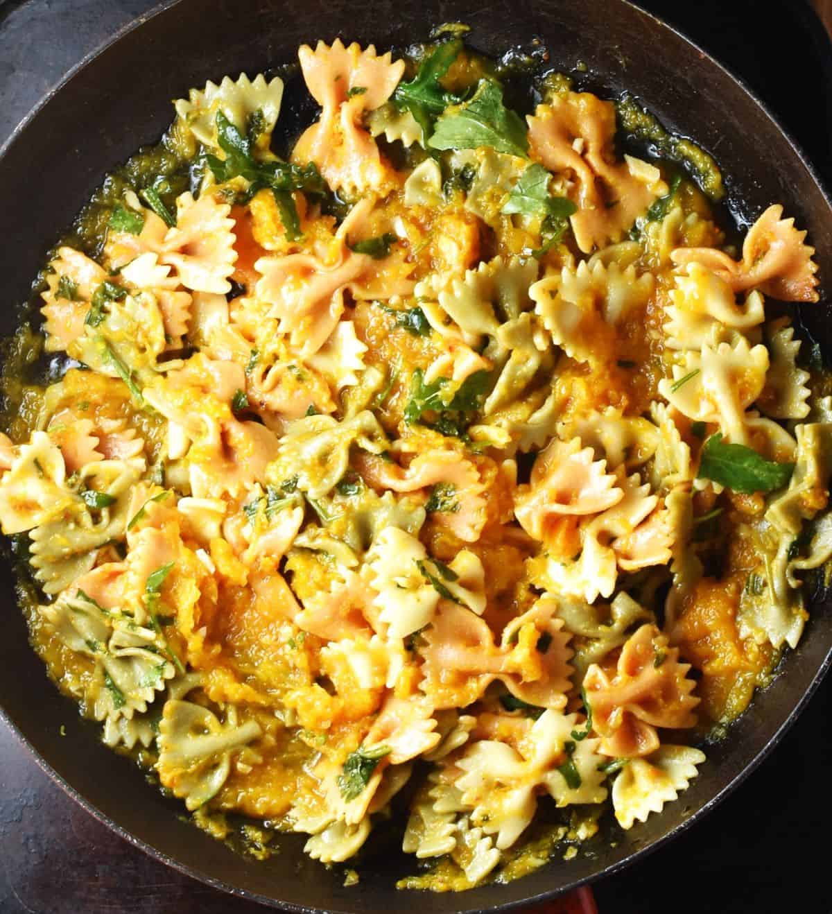 Farfalle pasta with butternut squash sauce in pan.