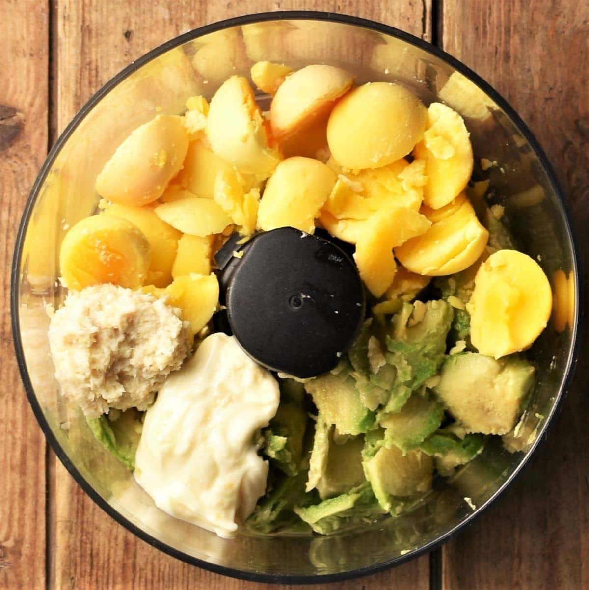 Egg yolks, mayonnaise and avocado in food processor.