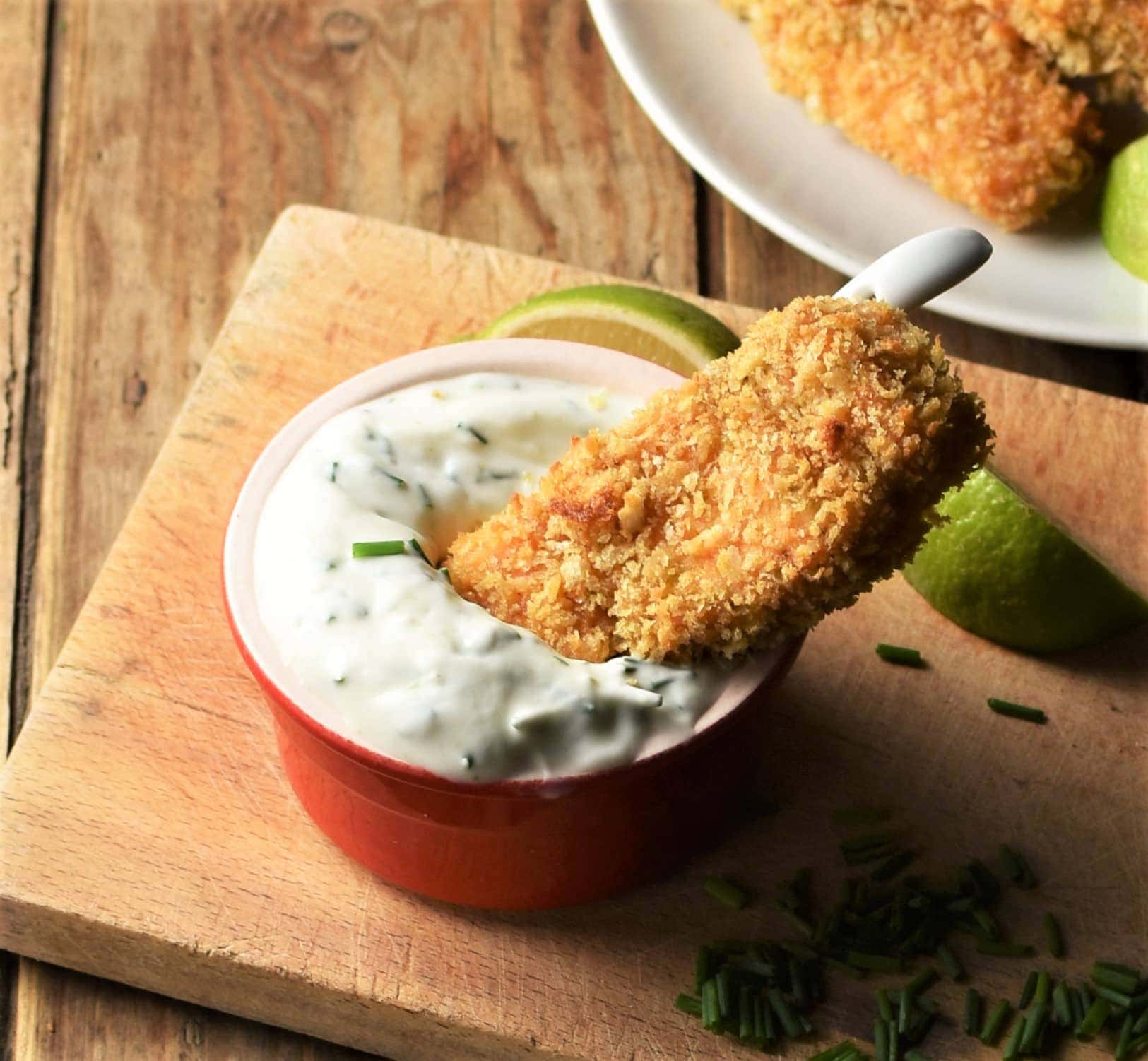 Crispy salmon finger dipped in yogurt in red dish.