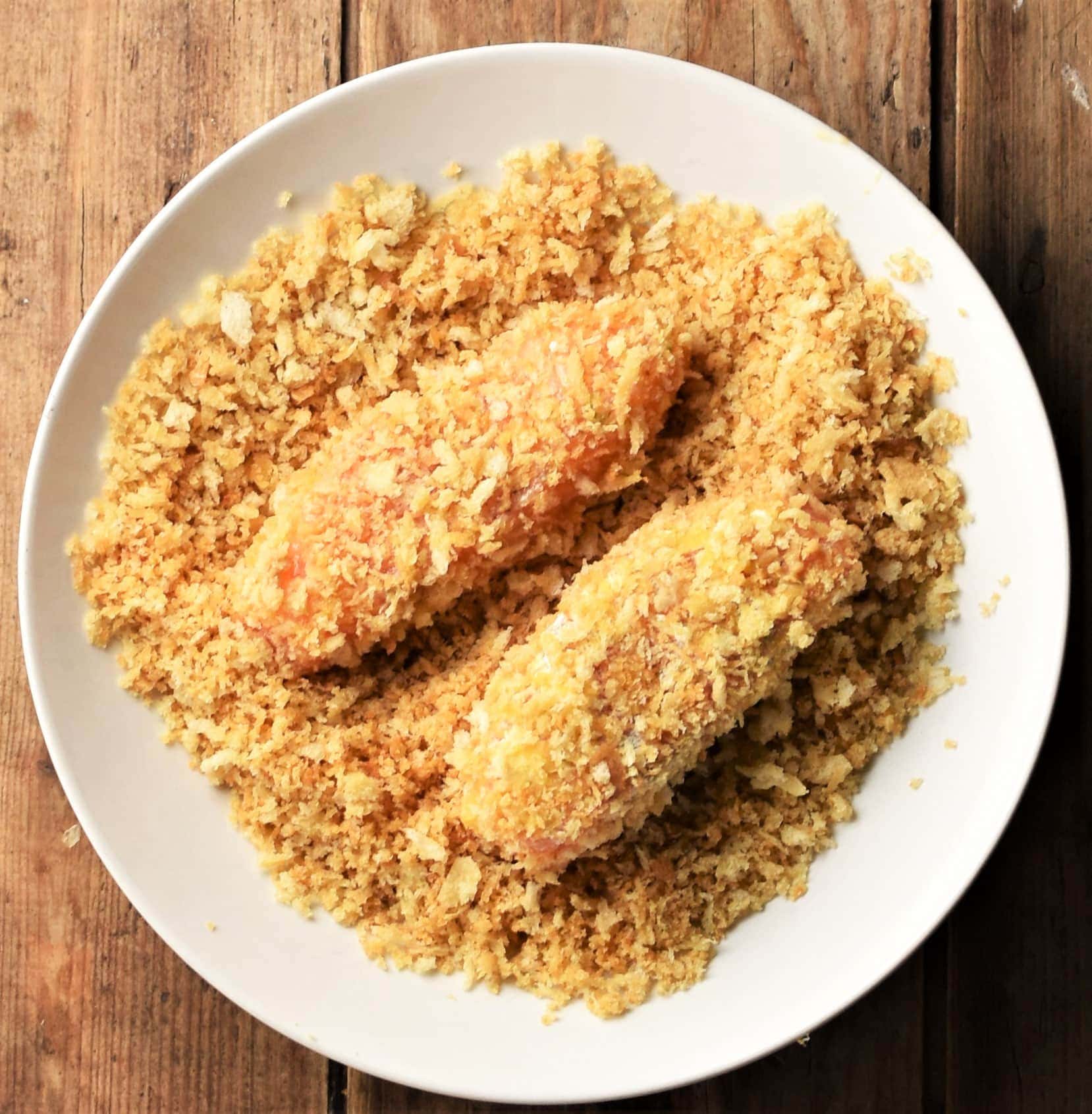 2 salmon fingers in breadcrumbs on white plate.