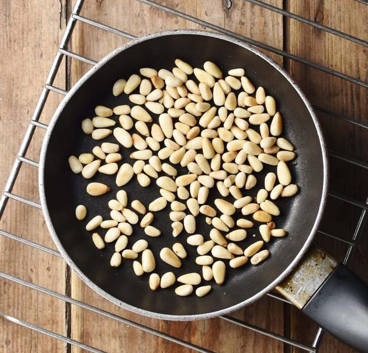 Pine nuts in small pan on rack.