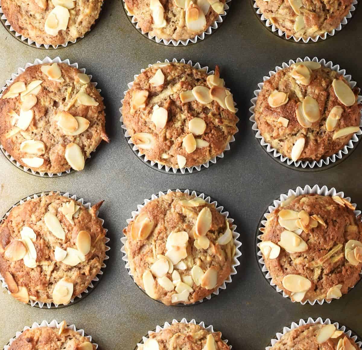 Top down view of baked gluten free apple muffins in white paper cases in muffin pan.