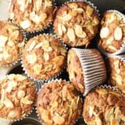 Close-up top down view of gluten free apple muffins in white paper cases clustered together.