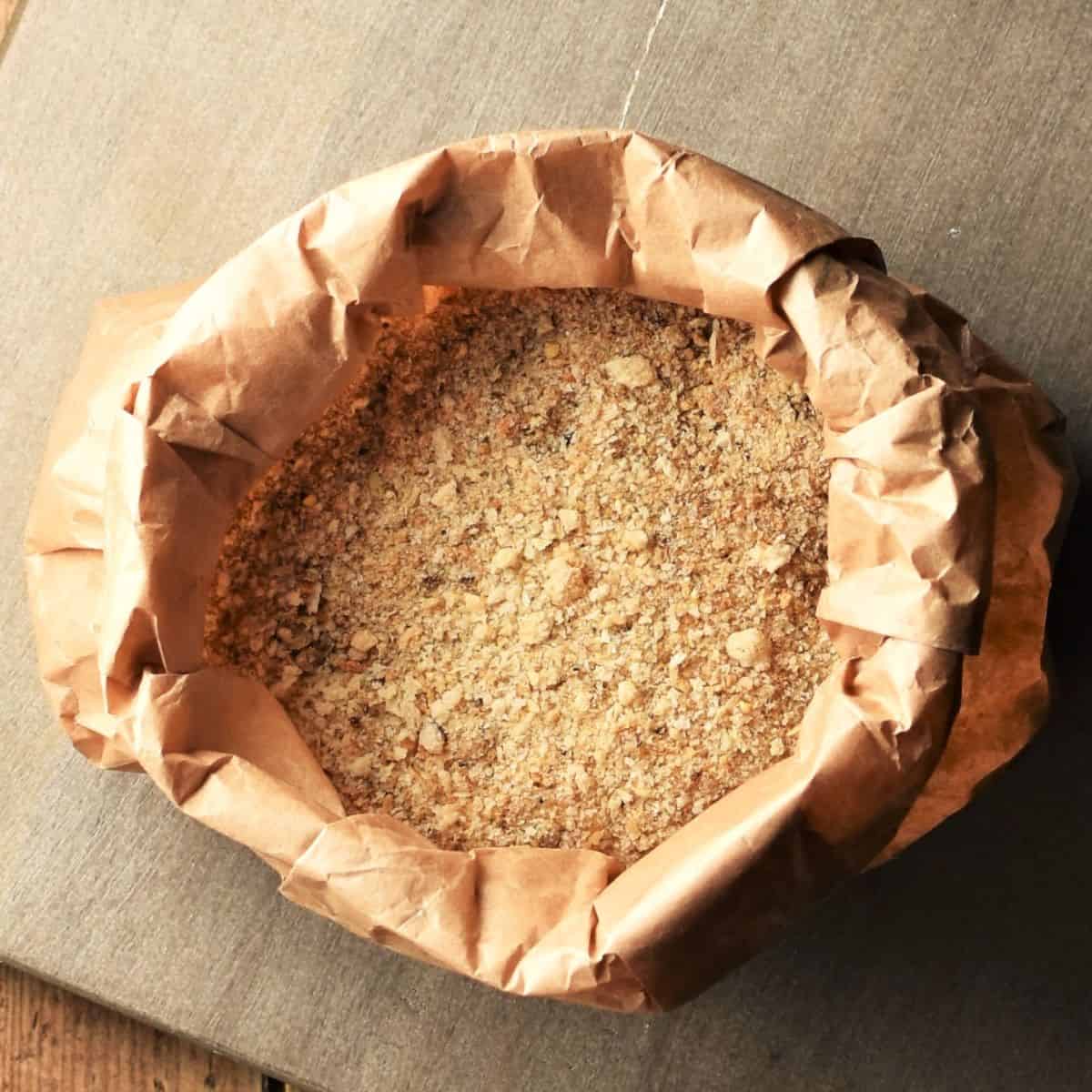 Top down view of homemade breadcrumbs in open paper bag.