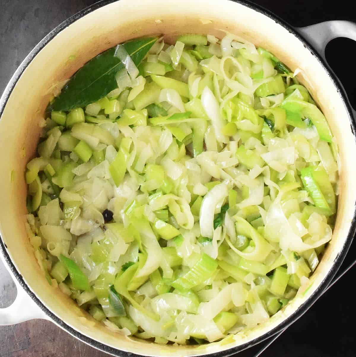 Vegetables with leek in large white pot.