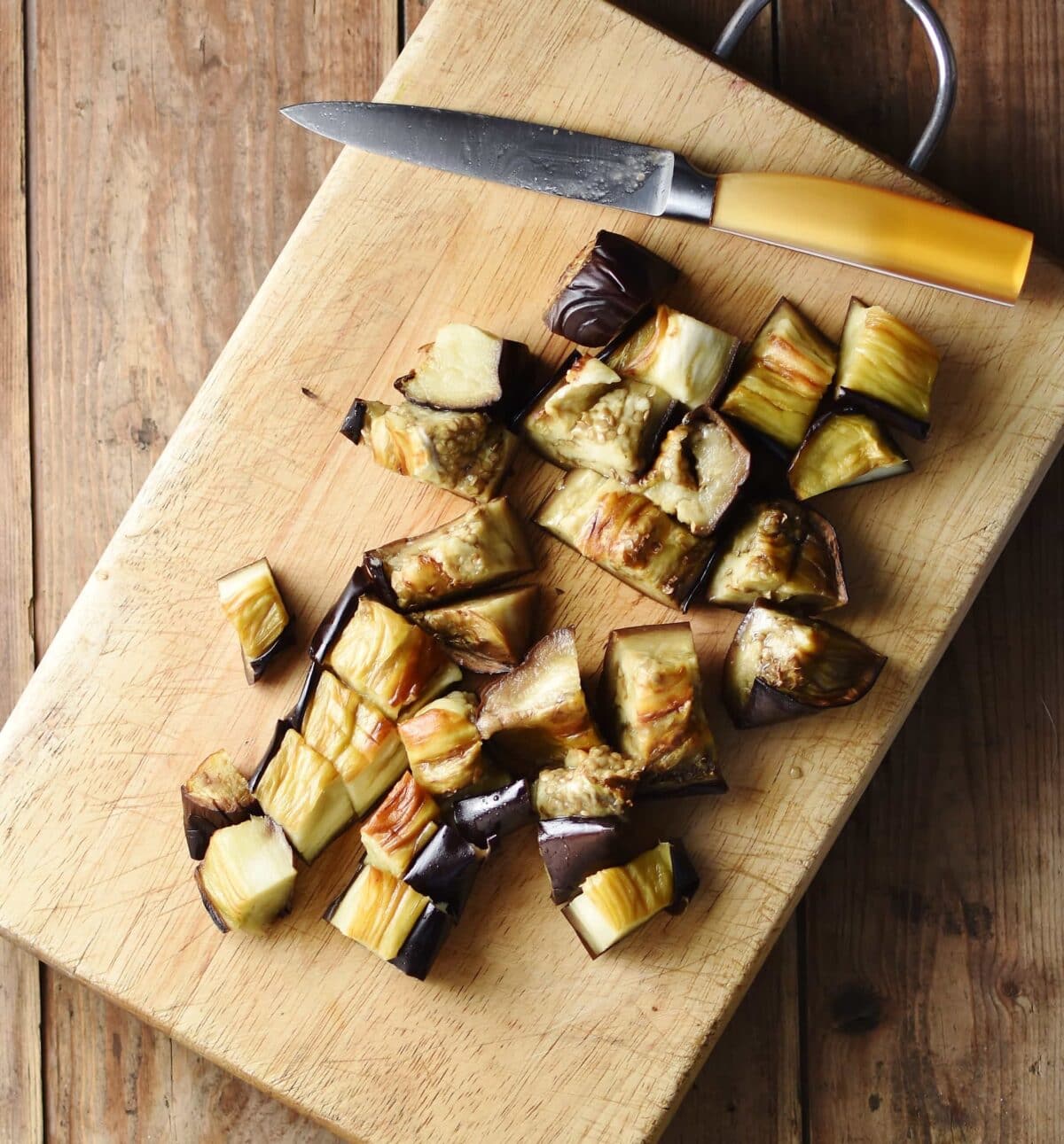 Chopped eggplant with knife of top of cutting board.