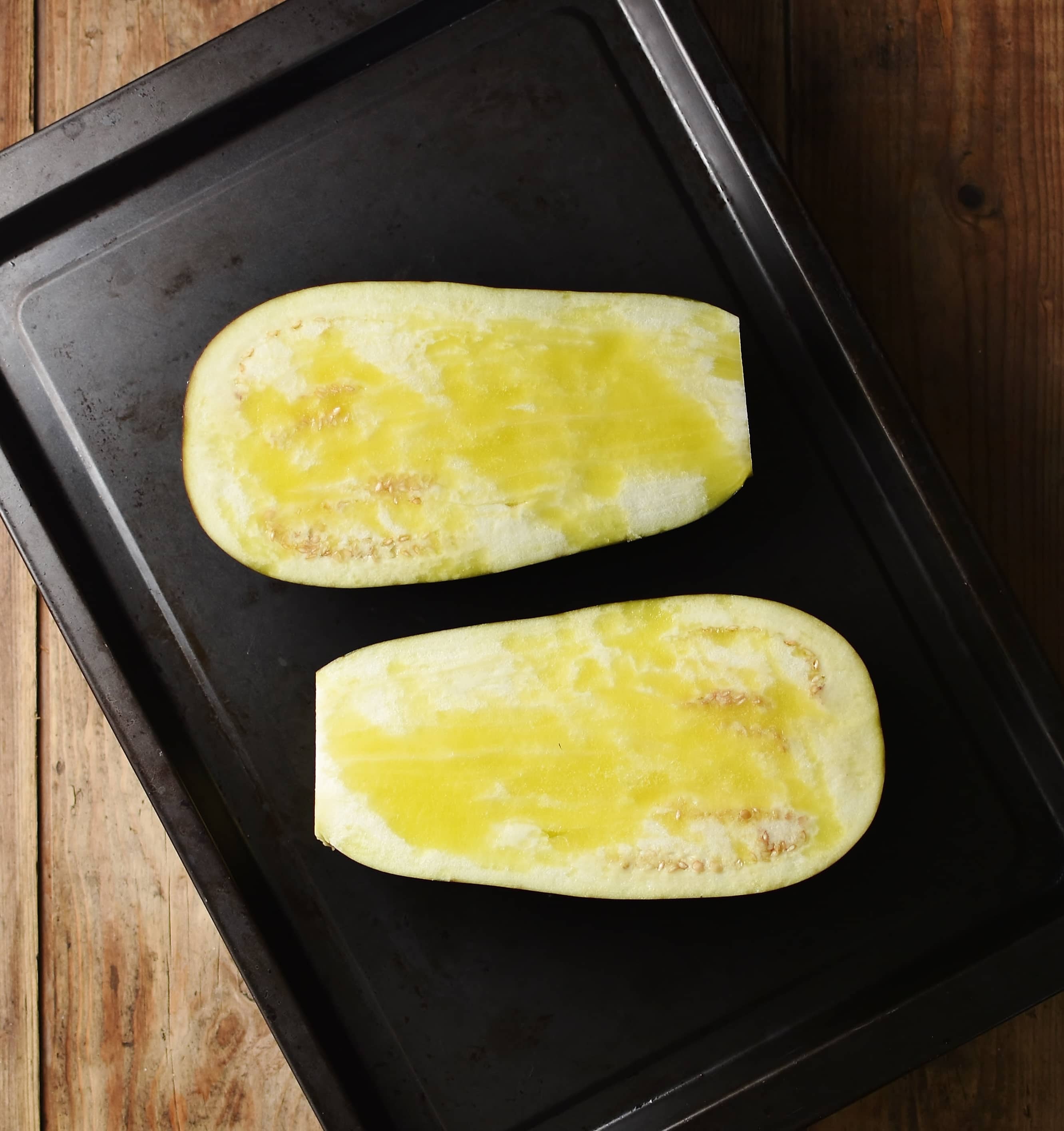 2 eggplant halves on top of dark tray.