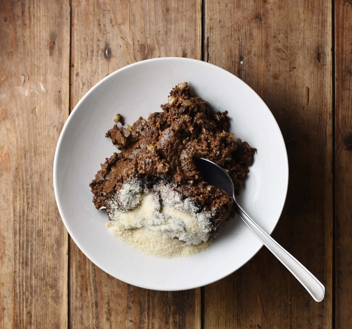 Mushroom mixture with breadcrumbs in white bowl with spoon.