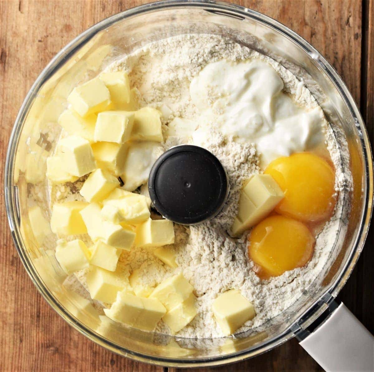 Cubed butter, egg yolks and flour in food processor bowl.