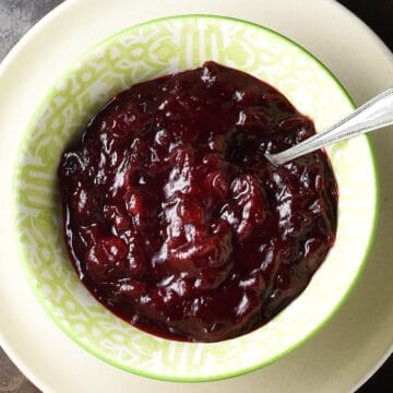 Top down view of cranberry sauce with honey in green bowl with spoon.