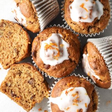 Top down view of dried cranberry muffins with glaze in white paper cases.