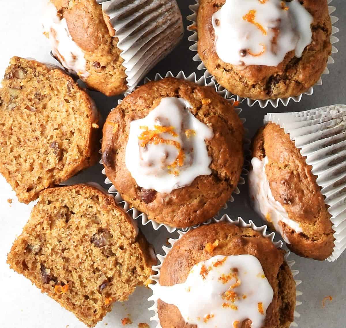 Top down view of dried cranberry muffins with glaze in white paper cases.