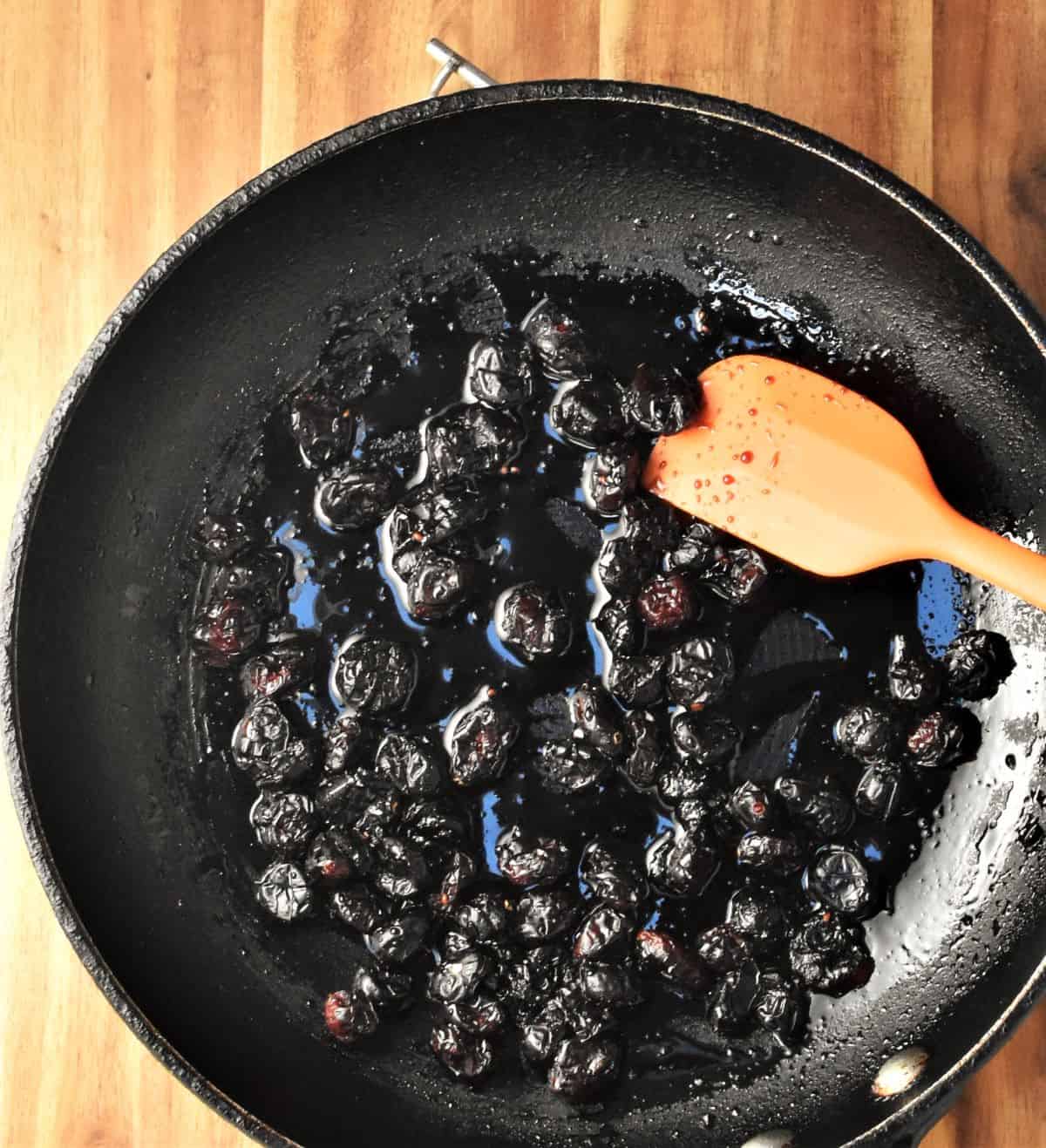 Making balsamic cranberry mixture in pan with orange spoon.