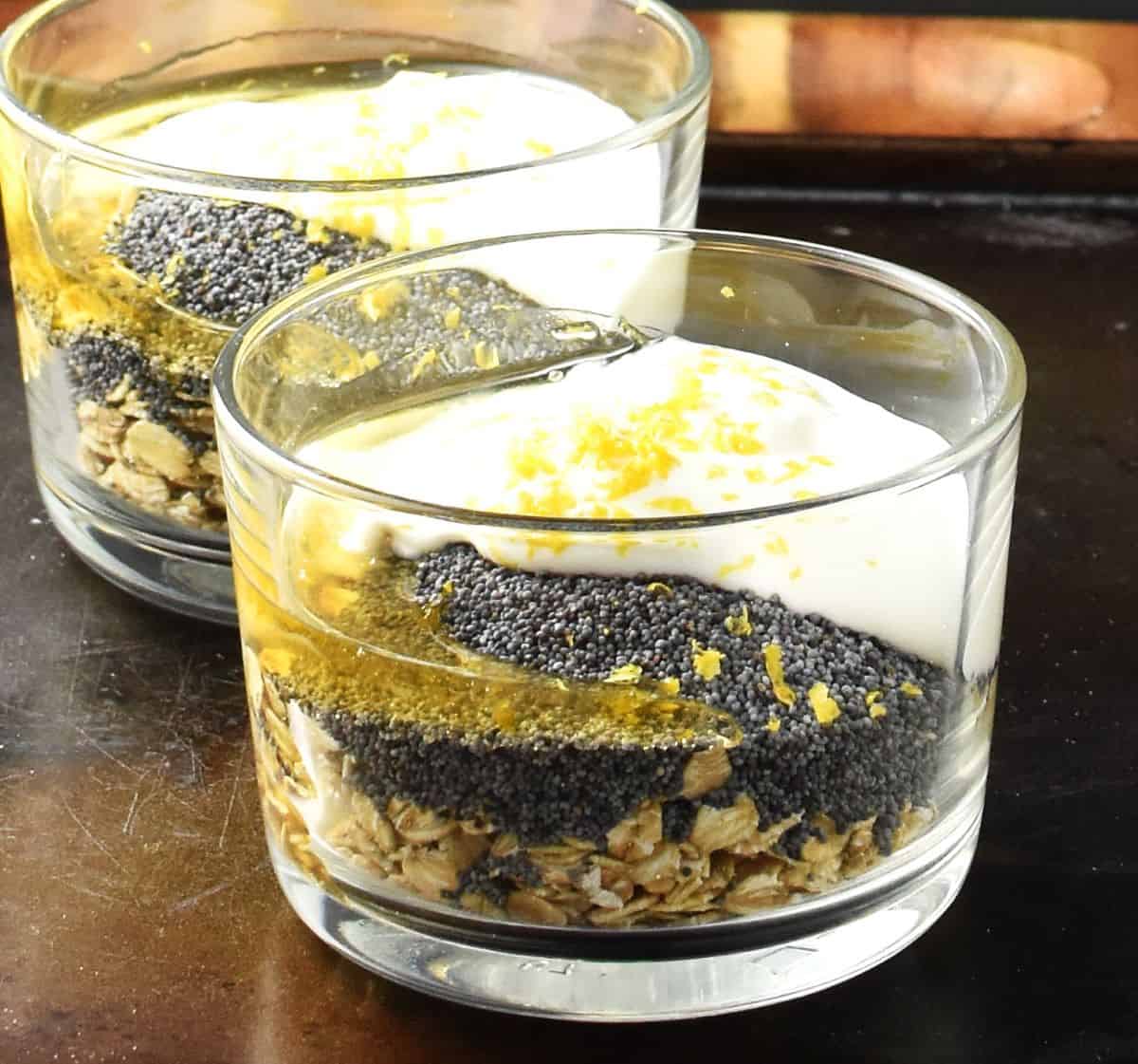 Side view of poppy seed overnight oats with lemon zest in 2 glasses.