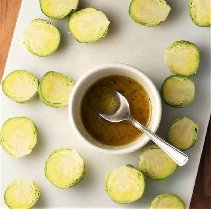 Halved brussels sprouts and oil mixture in bowl.