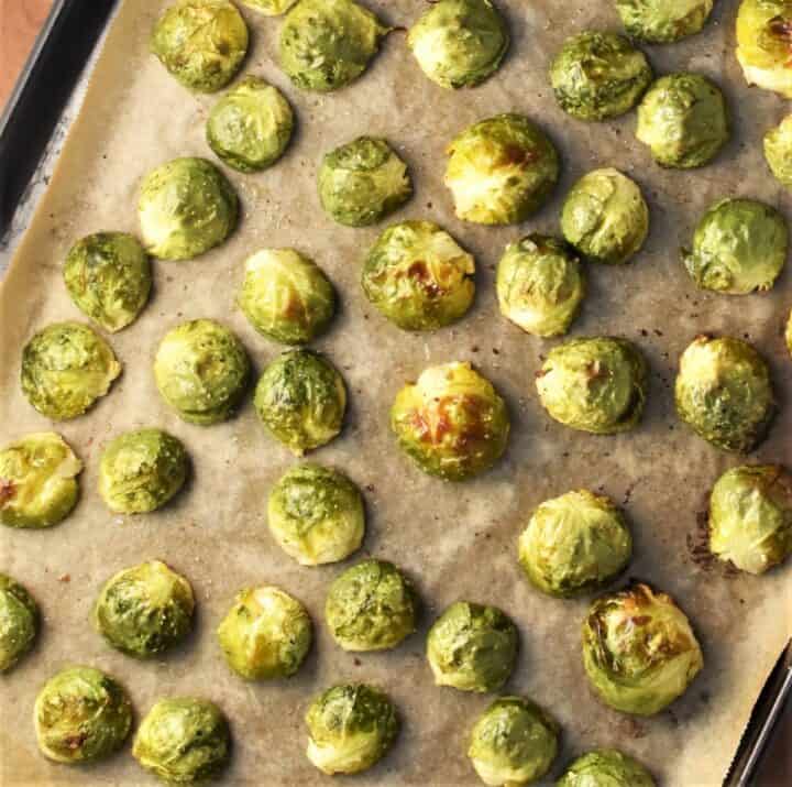 Halved roasted brussels sprouts on top of parchment.