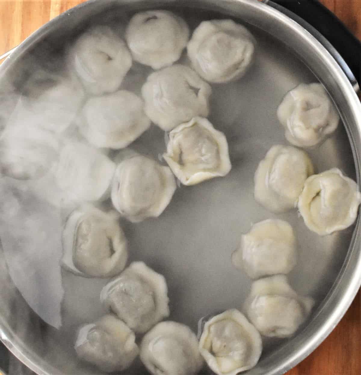 Top down view of boiling Polish uszka in large pot with water.