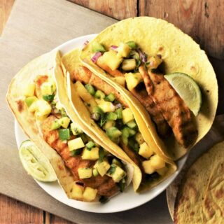 3 tortillas with chicken and pineapple salsa on plate.