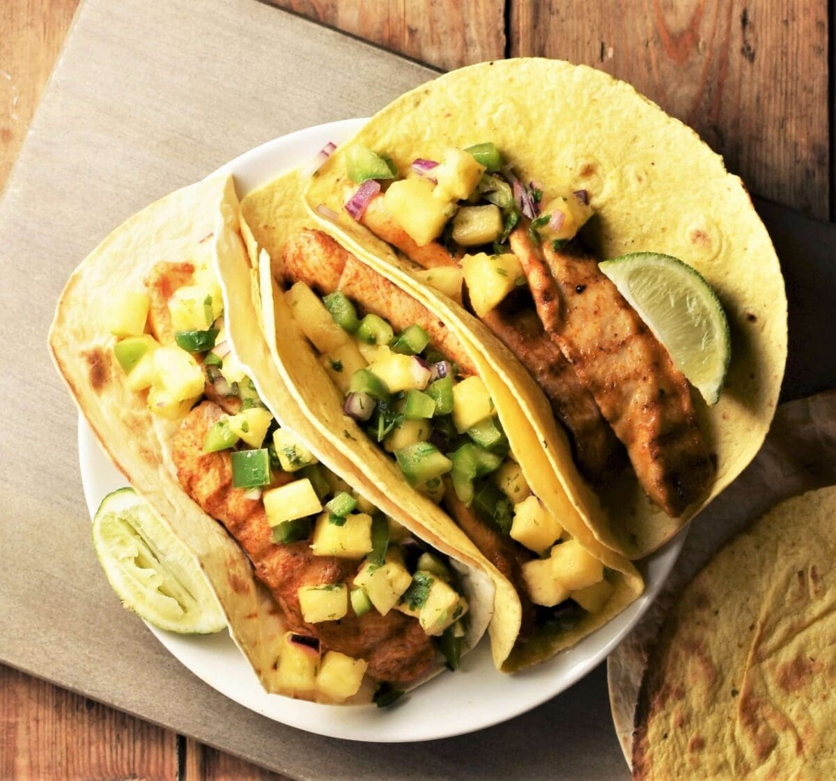 3 tortillas with chicken and pineapple salsa on plate.