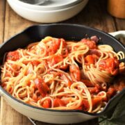 Side view of red pepper spaghetti in pan with fork.