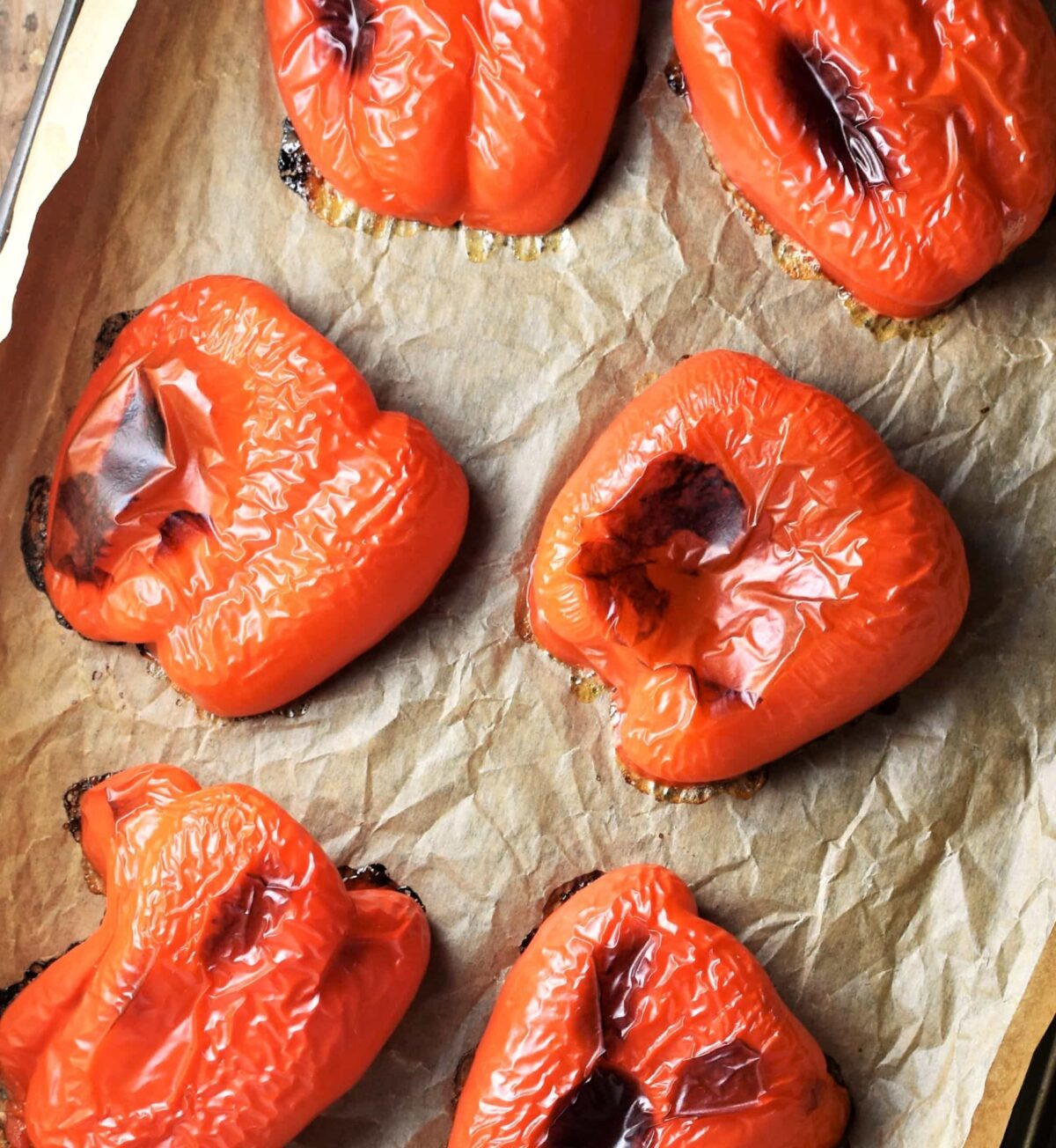 Roasted red bell pepper halves on top of parchment.