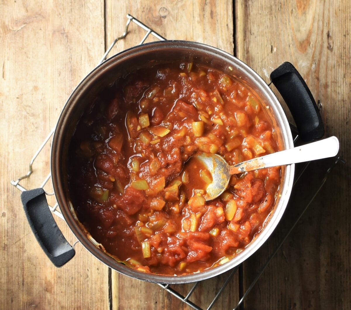 Tomato and onion sauce in pot with spoon.