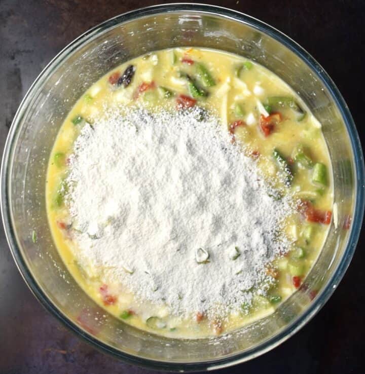 Asparagus muffin mixture with flour on top in large bowl.