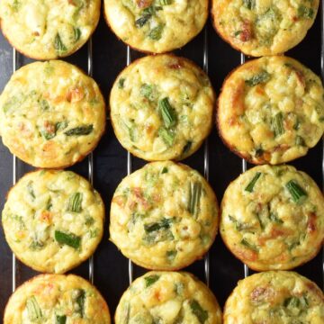 Top down view of 12 asparagus egg muffins on top of rack.