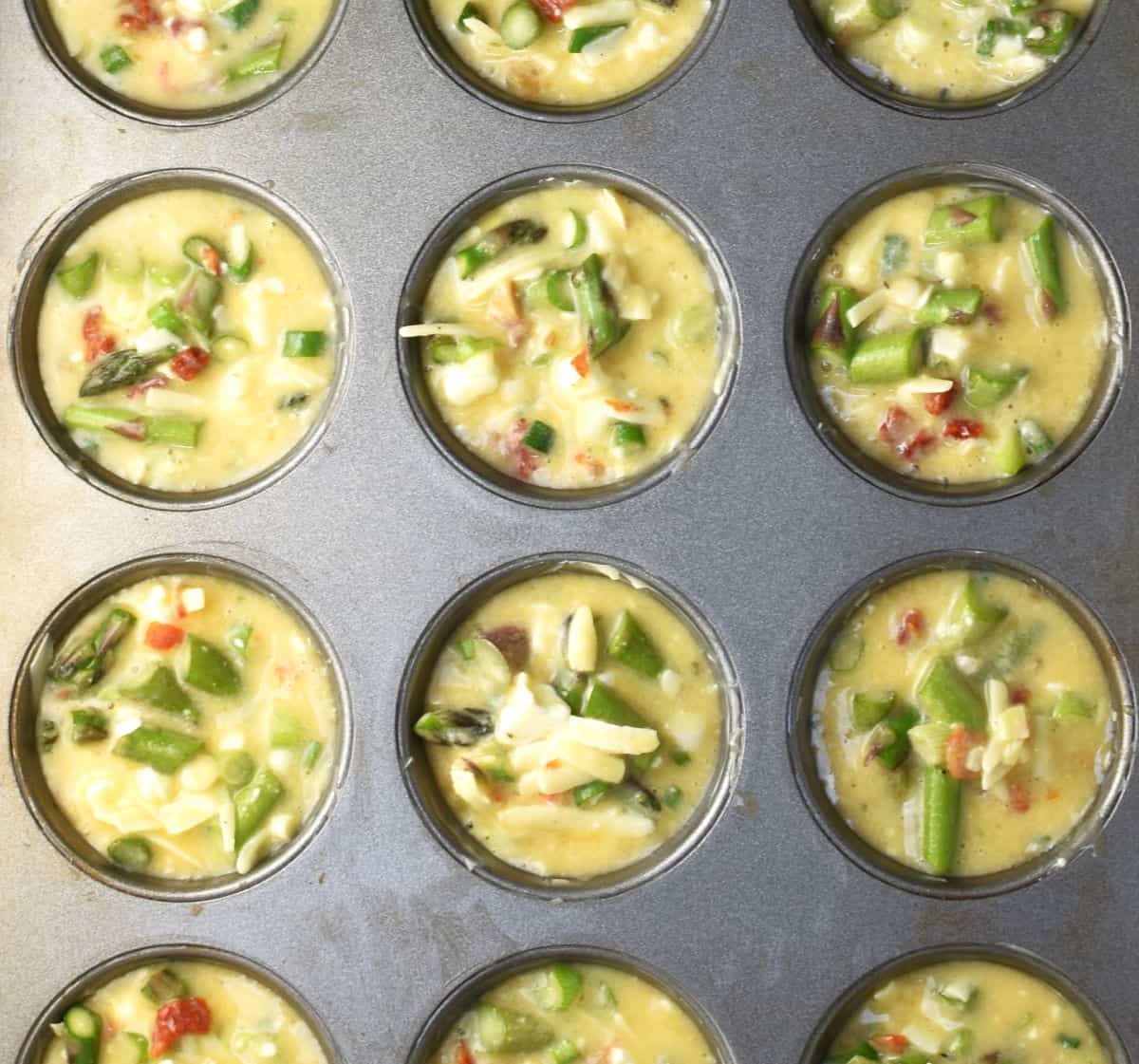 Egg and asparagus muffin batter in muffin pan.