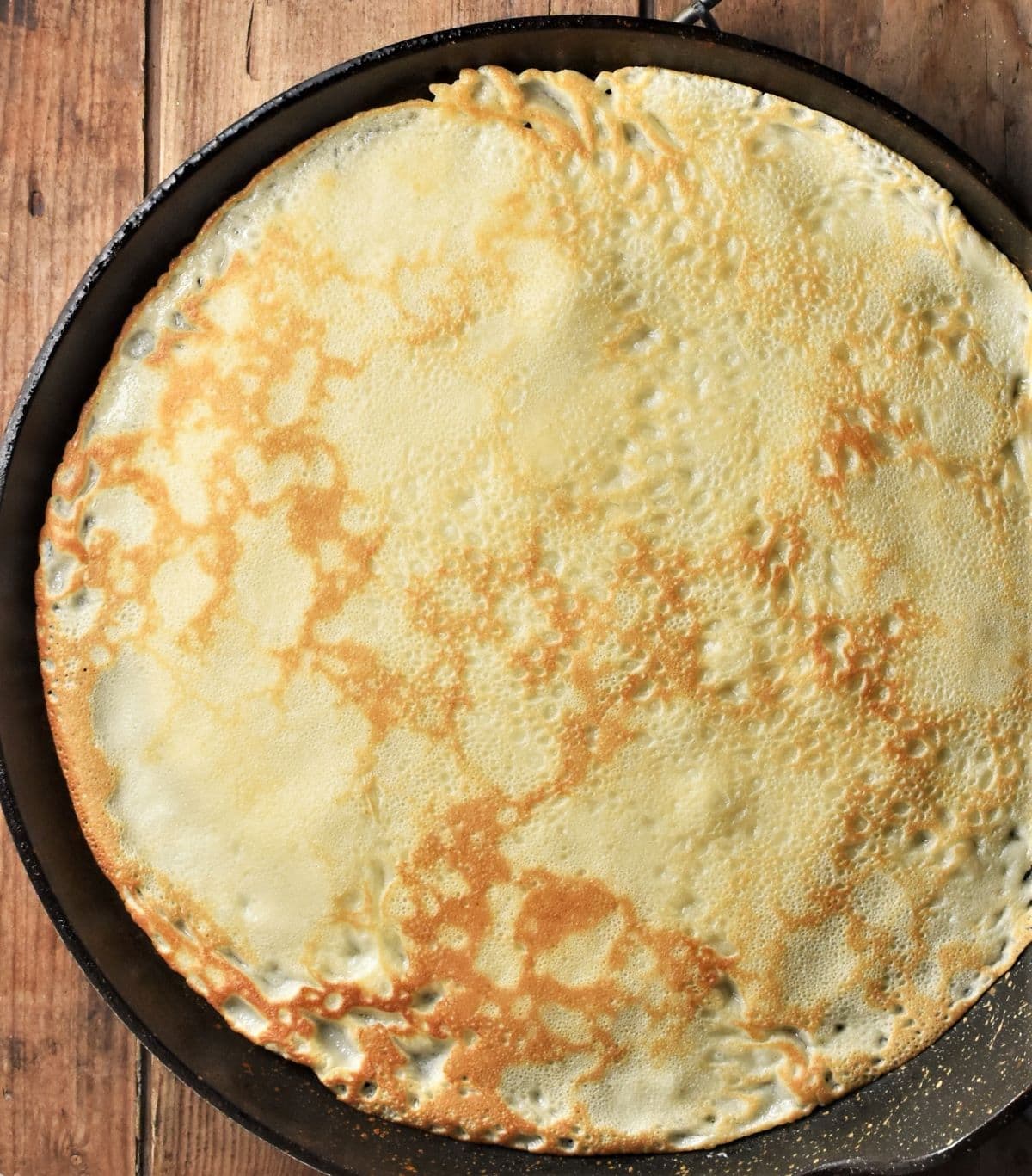 Large crepe on top of frying pan.
