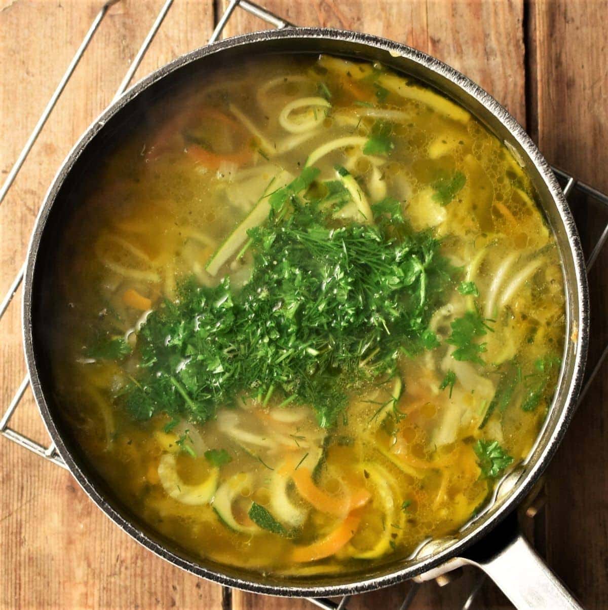 Spiralised vegetable soup with herbs in pot.