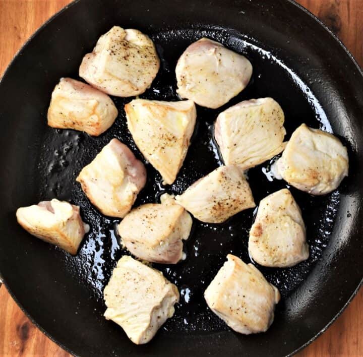Browned chunks of chicken breast in large pan.