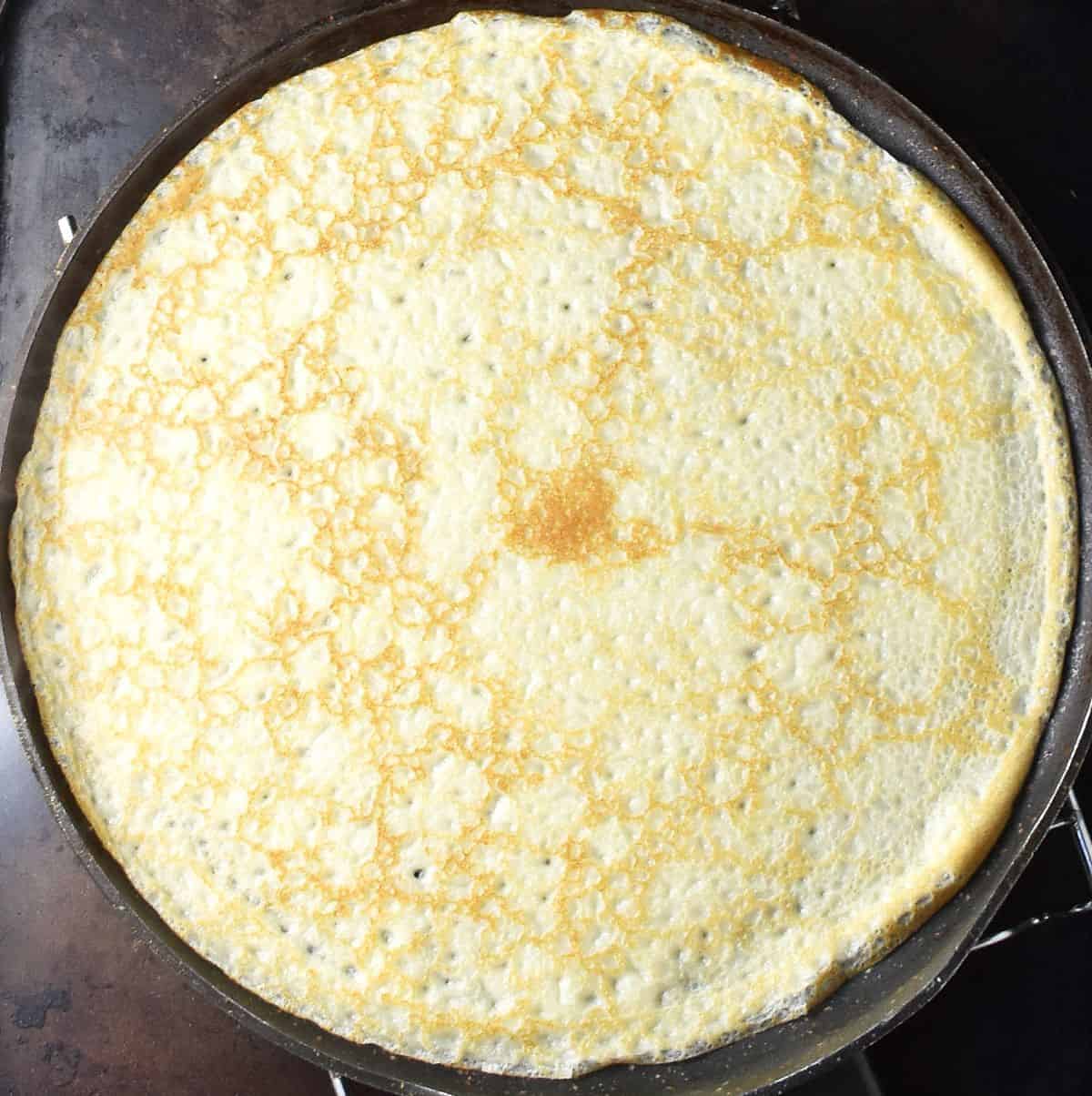 Top down view of one cooked nalesnik crepe in large pan.