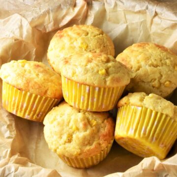 Top down view of cornmeal muffins in yellow cases on top of parchment.