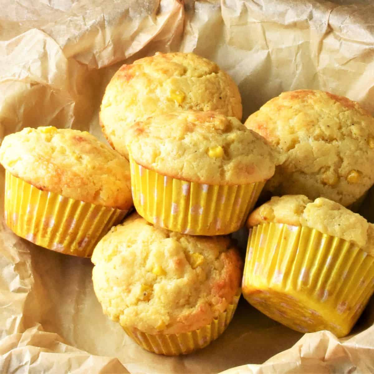 Top down view of cornmeal muffins in yellow cases on top of parchment.