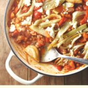 Top down partial view of fennel, vegetable and beans in large shallow white dish with spoon.