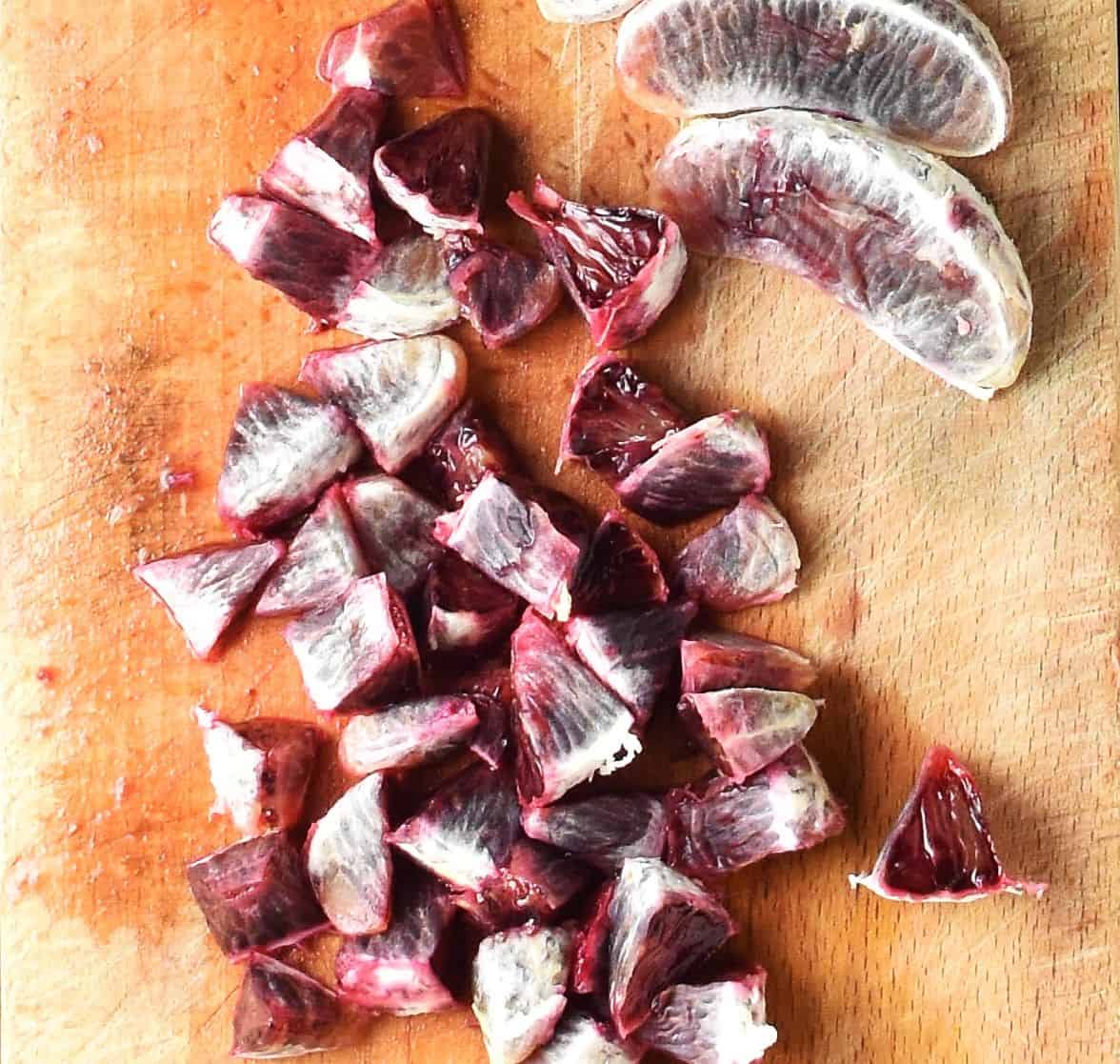 Peeled, chopped blood oranges on top of wooden board.