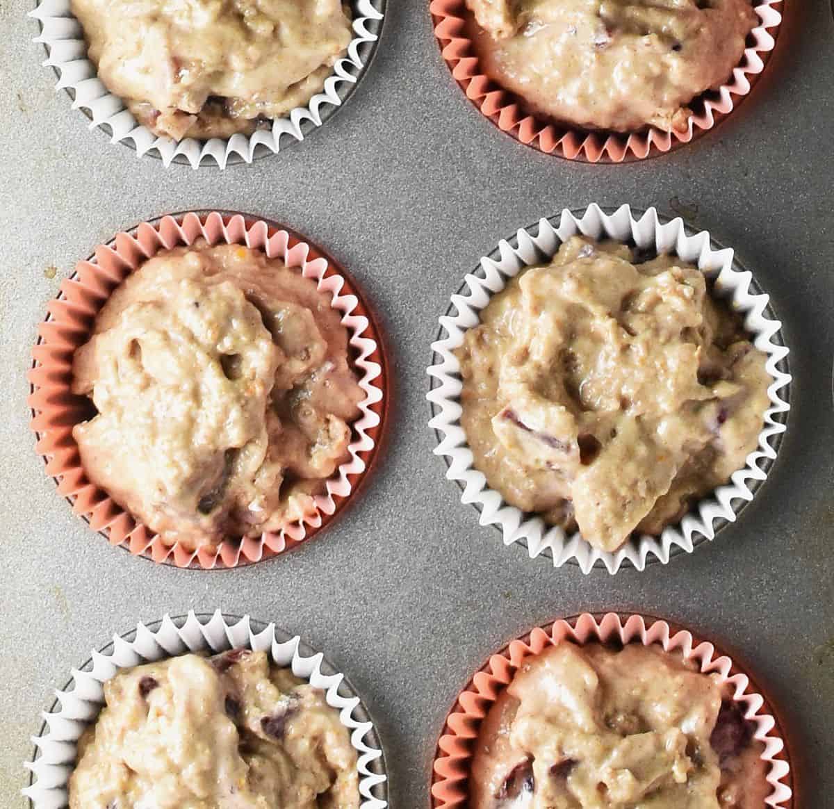 Top down view of blood orange muffin batter in muffin cases.