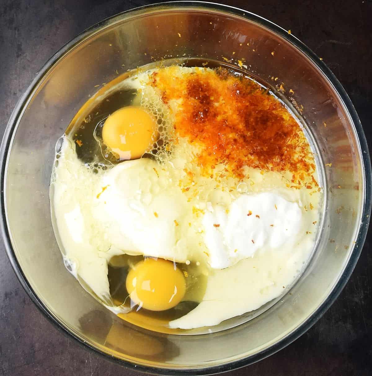 2 eggs, yogurt and blood orange zest in glass bowl.