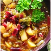 Top down view of beet greens vegetable soup with garnish of parsley, in purple bowl.