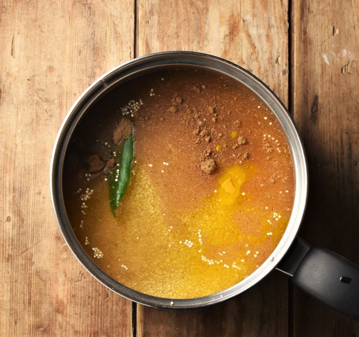 Quinoa with spices and bay leaf in pot.