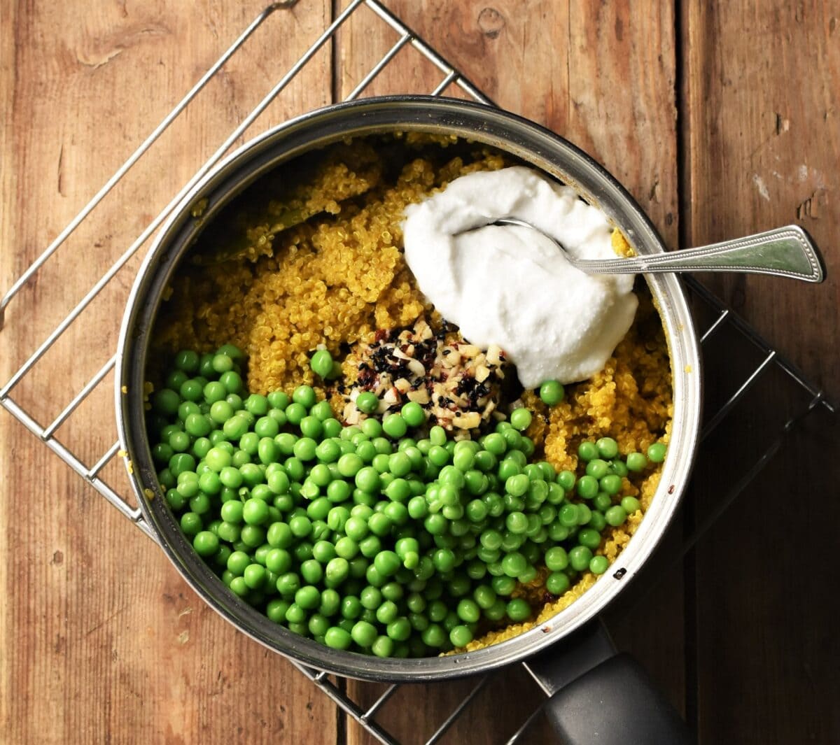 Peas, coconut milk and curry quinoa in pot with spoon.